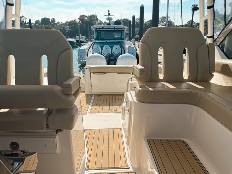 Slide: The Image of 2018 Pursuit DC 325 Dual Console boat interior with beige seating and wooden flooring. - 23