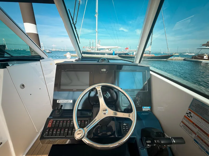 Slide: The Image of 2018 Pursuit DC 325 Dual Console helm with steering wheel, navigation screens, and marina view. - 27