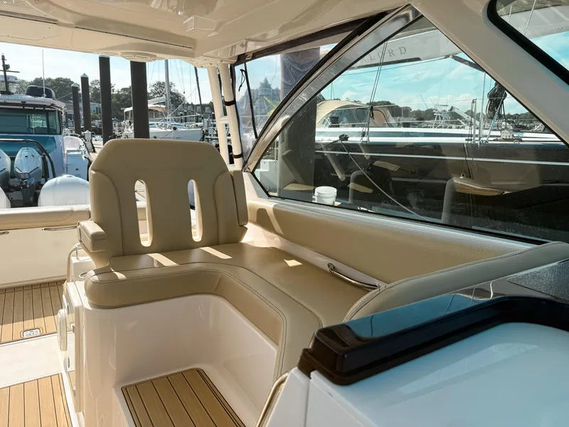 Slide: The Image of 2018 Pursuit DC 325 Dual Console interior with beige seating and marina view. - 29