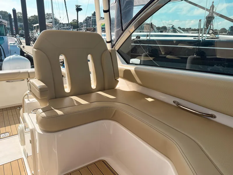 Slide: The Image of 2018 Pursuit DC 325 Dual Console boat interior with beige seating and wooden deck. - 30