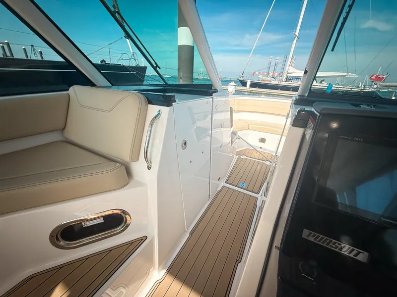 Slide: The Image of 2018 Pursuit DC 325 Dual Console boat interior with beige seating and wooden flooring. - 32