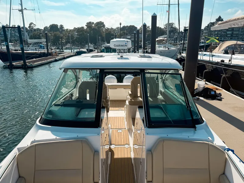 Slide: The Image of 2018 Pursuit DC 325 Dual Console boat docked at marina, featuring spacious seating and modern design. - 36