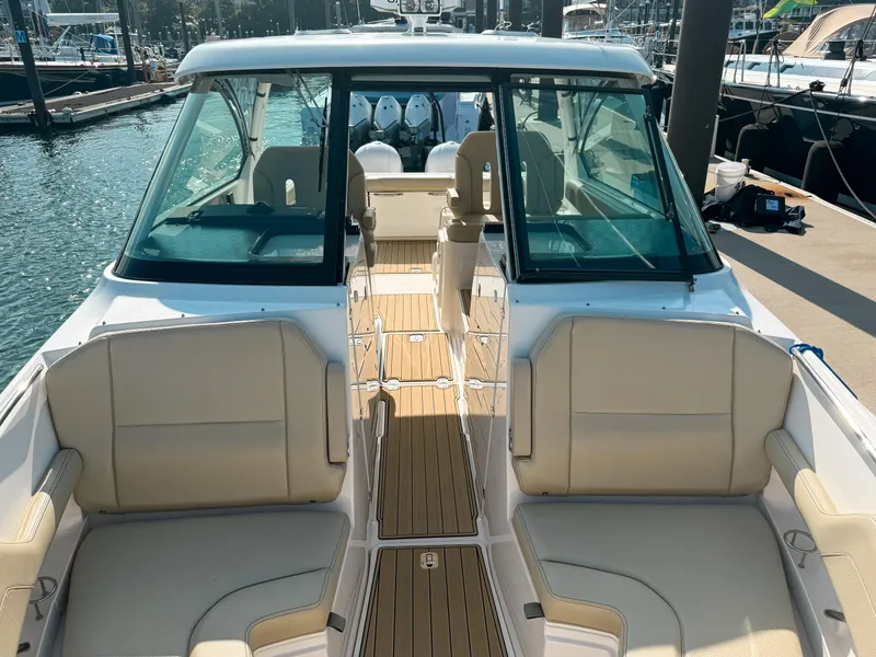 Slide: The Image of 2018 Pursuit DC 325 Dual Console boat with spacious seating and sleek design at a marina. - 37