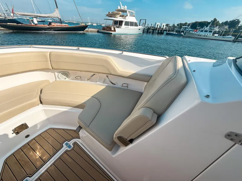 Slide: The Image of 2018 Pursuit DC 325 Dual Console boat interior with beige seating, docked in a marina. - 38