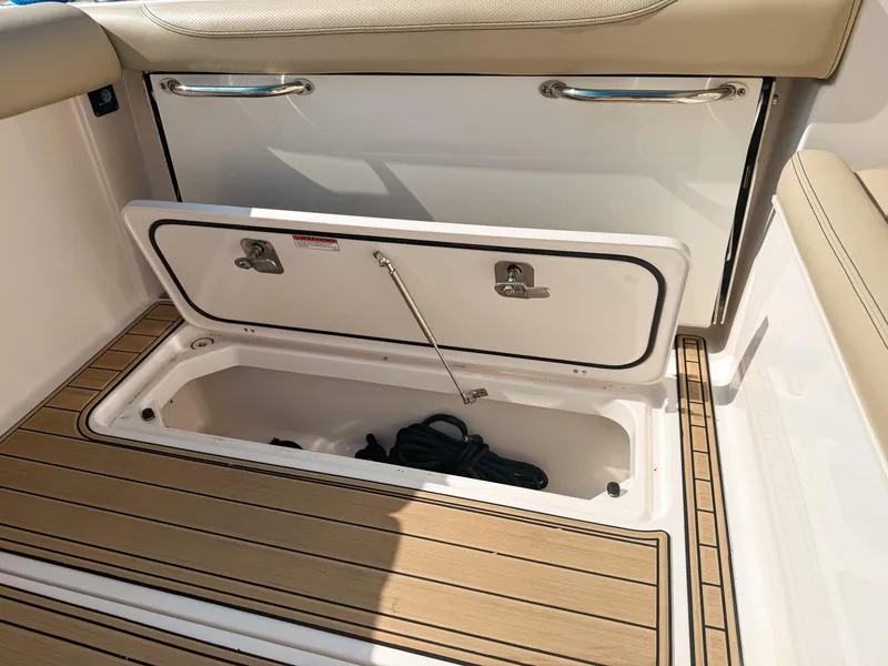 Slide: The Image of 2018 Pursuit DC 325 Dual Console storage compartment with open hatch and teak flooring. - 42