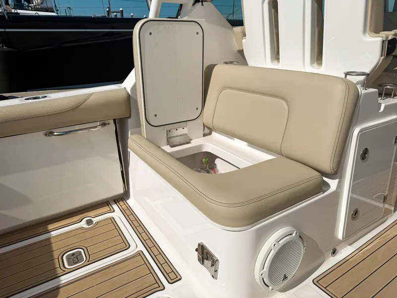 Slide: The Image of 2018 Pursuit DC 325 Dual Console boat interior with beige seating and storage compartment. - 46