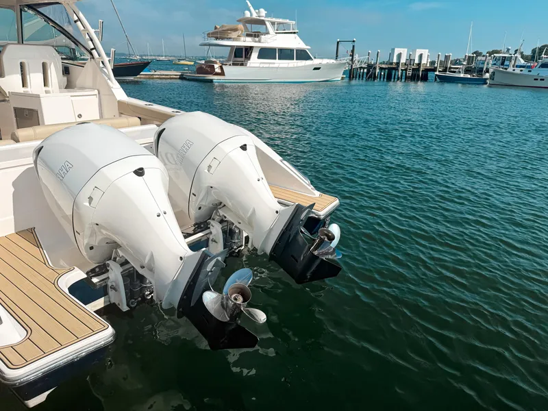 Slide: The Image of 2018 Pursuit DC 325 Dual Console with twin outboard engines docked in a marina. - 7
