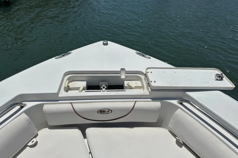 Slide: The Image of 2019 Sea Hunt Ultra 225 boat bow with anchor storage, white seating, and calm water view. - 10