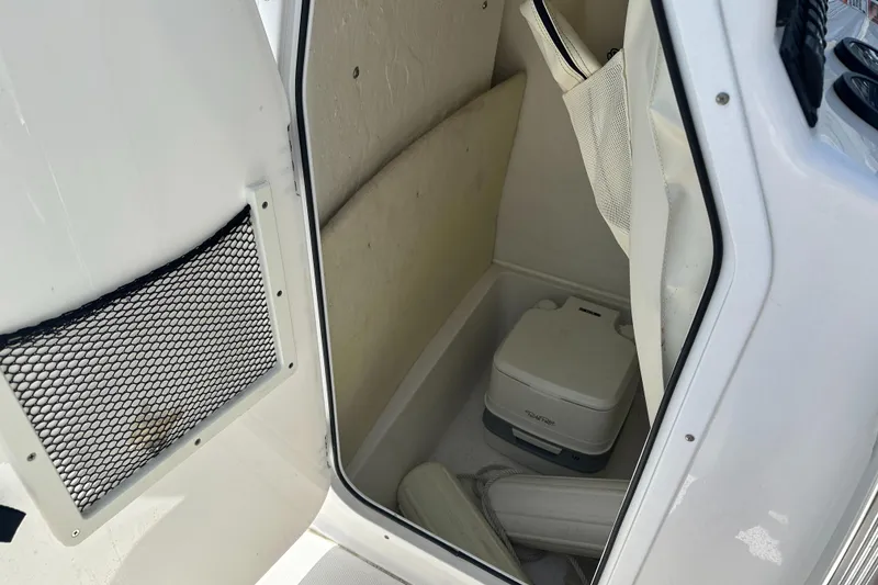 Slide: The Image of 2019 Sea Hunt Ultra 225 boat storage compartment with portable toilet and netted pocket. - 24
