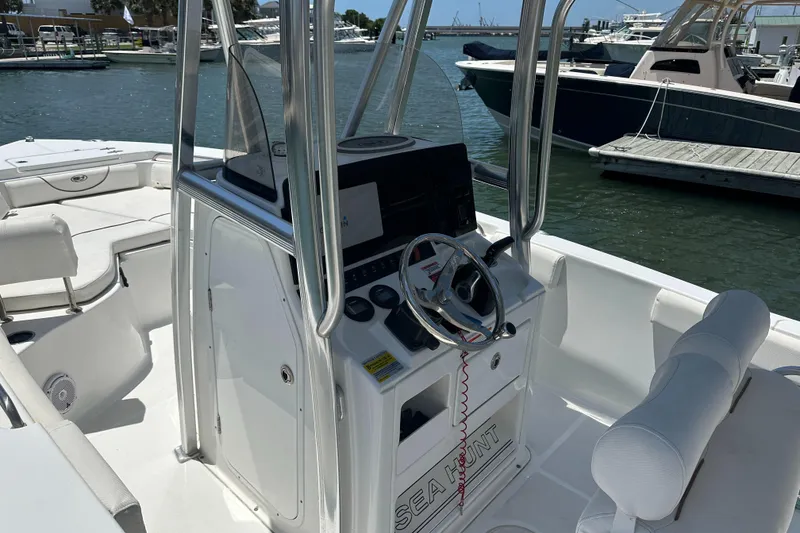 Slide: The Image of 2019 Sea Hunt Ultra 225 boat interior with steering console and seating, docked at marina. - 6