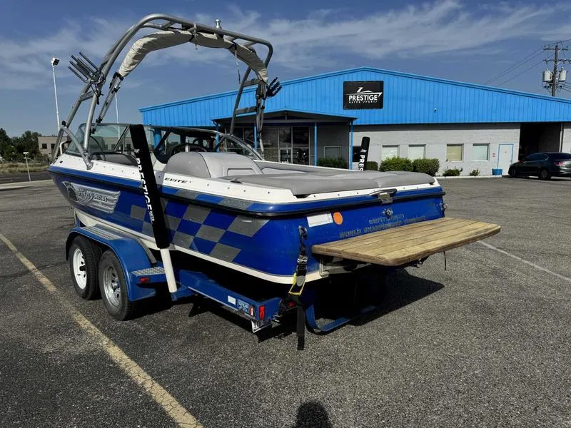 Slide: The Image of 2005 Centurion Elite boat on trailer in parking lot, blue building in background. - 5