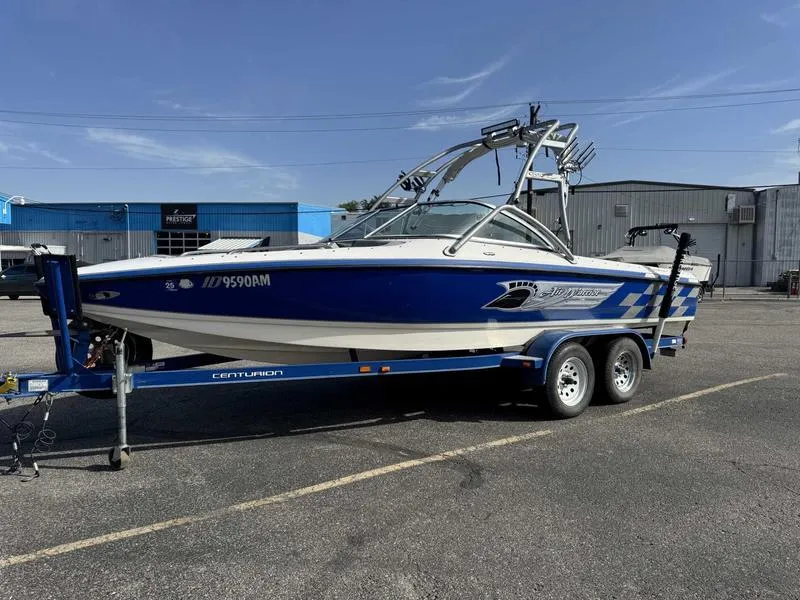 Slide: The Image of 2005 Centurion Elite boat on trailer in parking lot, blue and white design. - 6