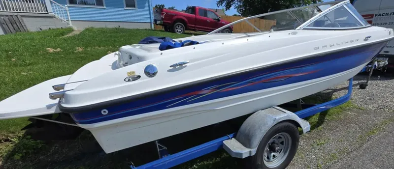 Slide: The Image of 2006 Bayliner 205 BR boat on trailer, white and blue design, parked outdoors. - 2