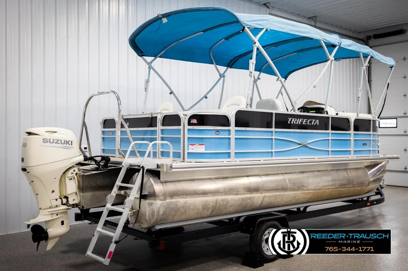 Slide: The Image of 2020 Trifecta 20 RFC CS pontoon boat with Suzuki motor and blue canopy in showroom. - 6