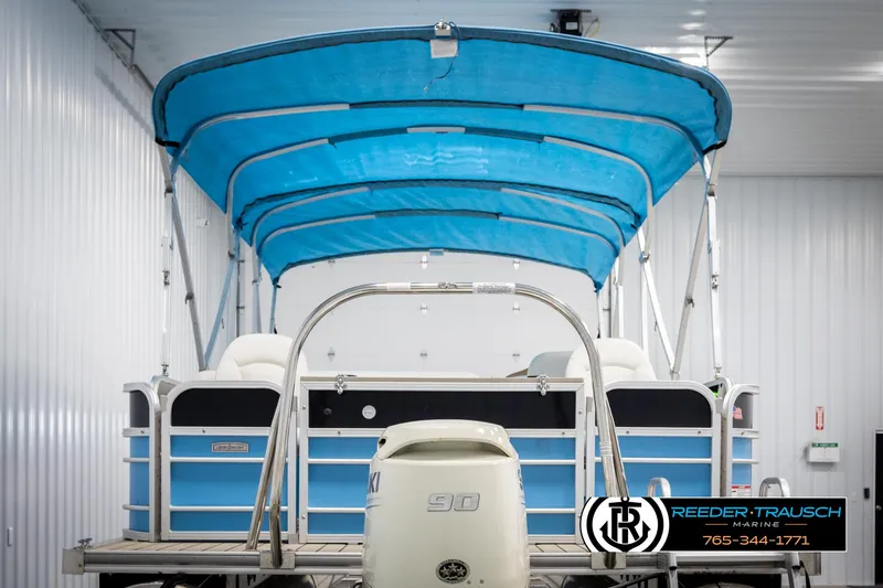 Slide: The Image of 2020 Trifecta 20 RFC CS pontoon boat with blue canopy in indoor storage. - 7