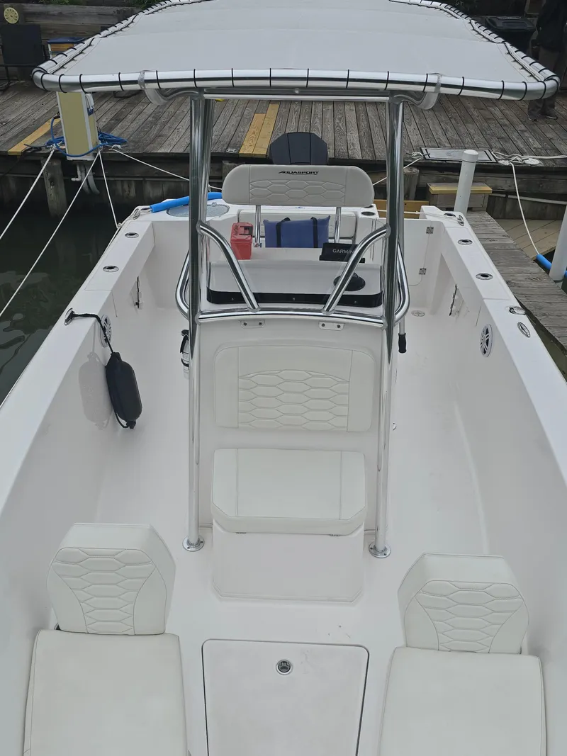 Slide: The Image of 2024 Aquasport 2200 Center Console boat with T-top and seating, docked at marina. - 4
