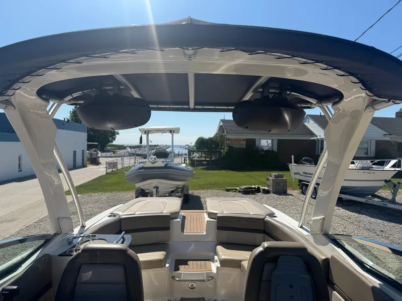 Slide: The Image of 2011 Sea Ray 250 SLX boat with spacious seating and canopy, docked under clear blue sky. - 21