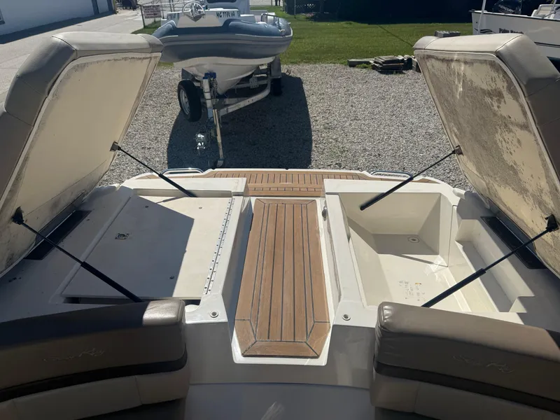 Slide: The Image of 2011 Sea Ray 250 SLX boat with open storage compartments and wooden deck. - 24