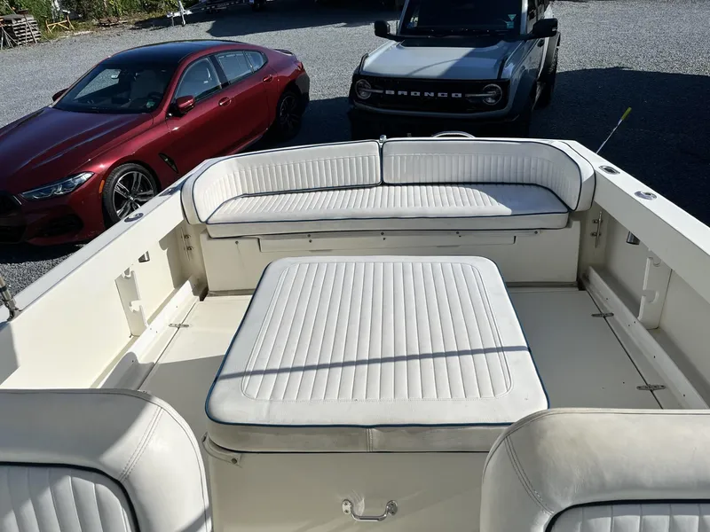 Slide: The Image of 2001 Limestone 24' Express Cruiser interior with white seating, parked near red and gray vehicles. - 10