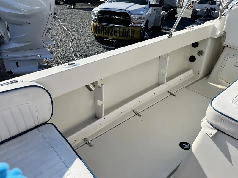 Slide: The Image of 2001 Limestone 24' Express Cruiser interior with seating and storage, parked near a truck. - 11