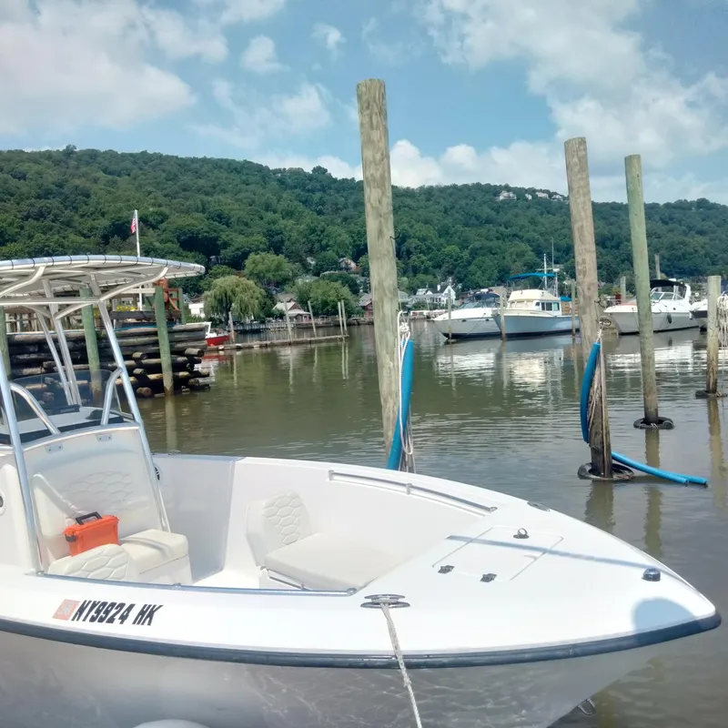 Slide: The Image of 2024 Aquasport 2200 Center Console boat docked in a scenic marina. - 1