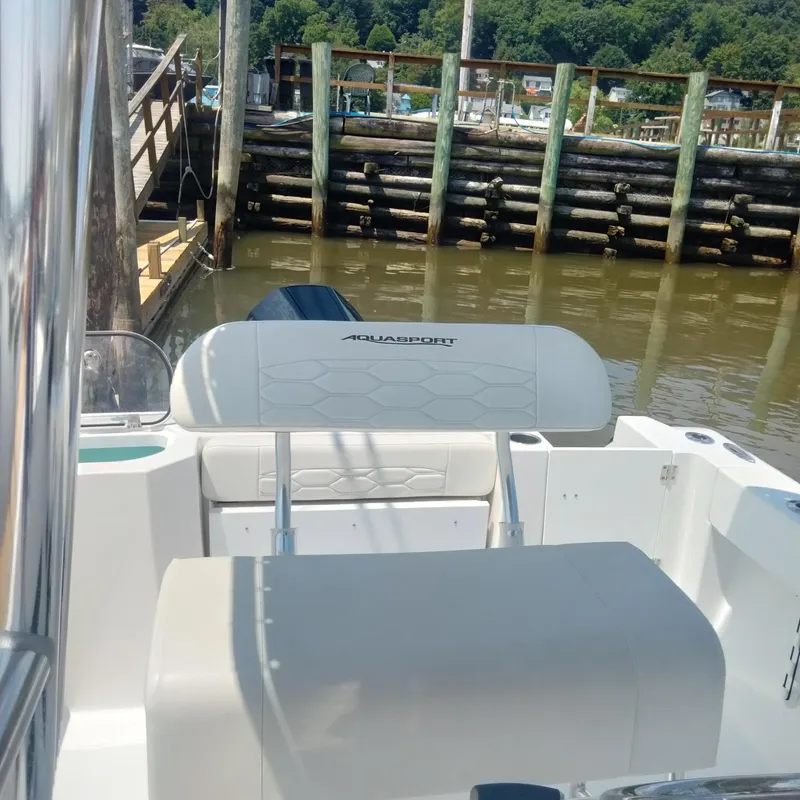 Slide: The Image of 2024 Aquasport 2200 Center Console boat docked by wooden pier. - 10