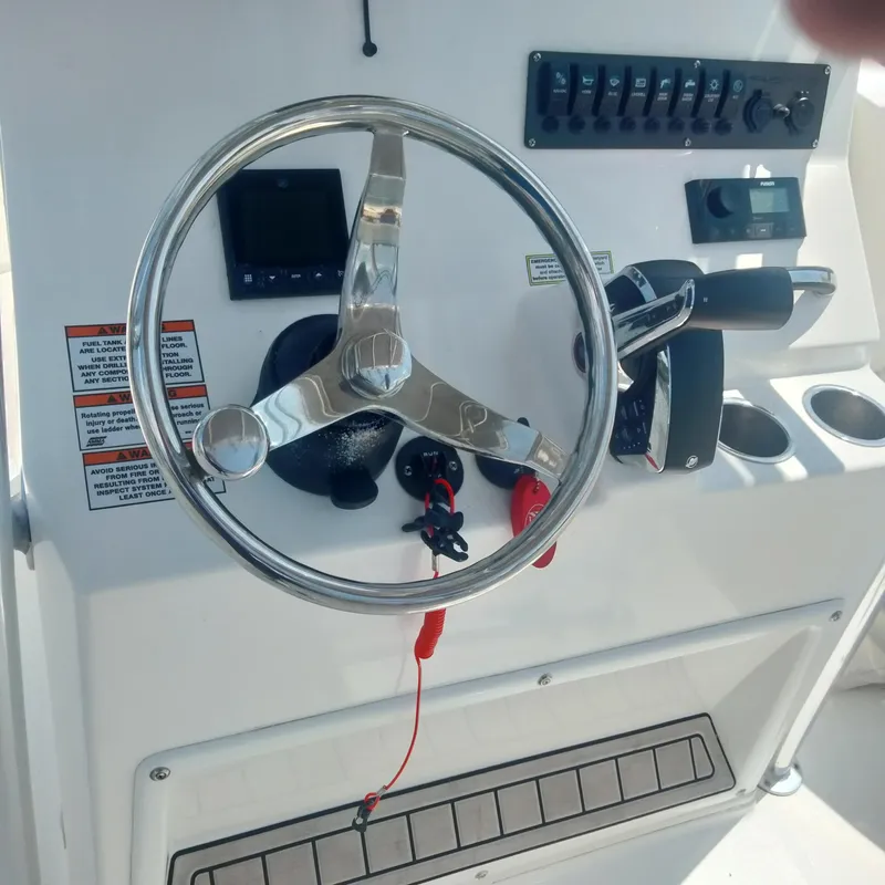 Slide: The Image of 2024 Aquasport 2200 Center Console steering wheel and control panel. - 2