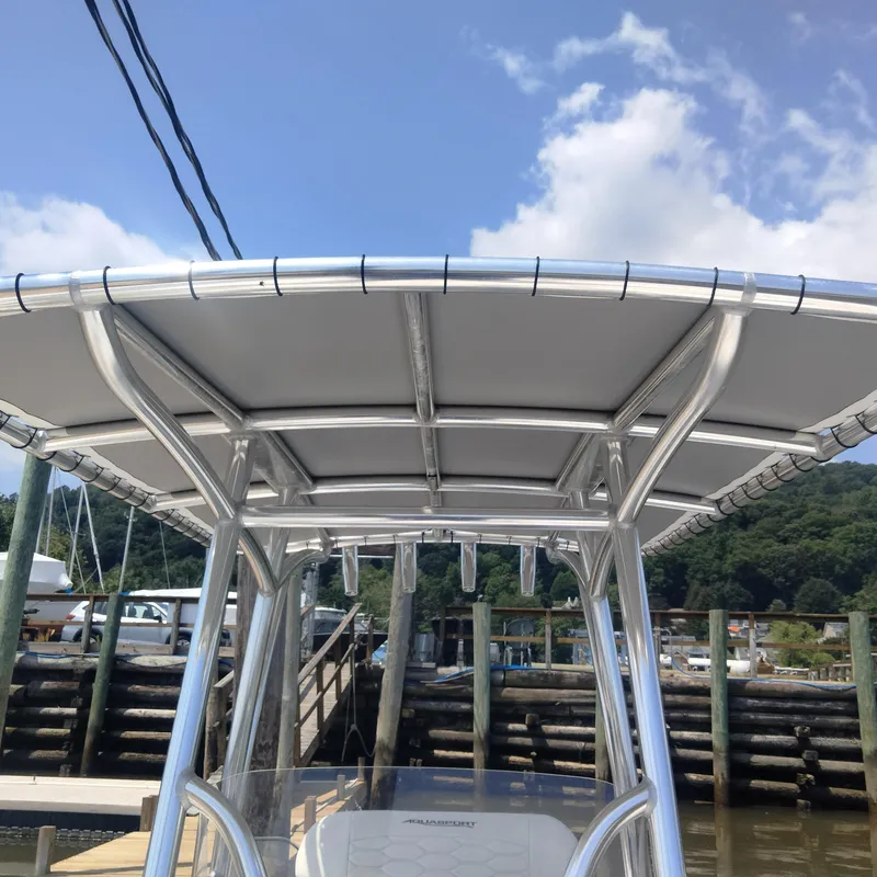 Slide: The Image of 2024 Aquasport 2200 Center Console boat with T-top at a dock, under a clear sky. - 6