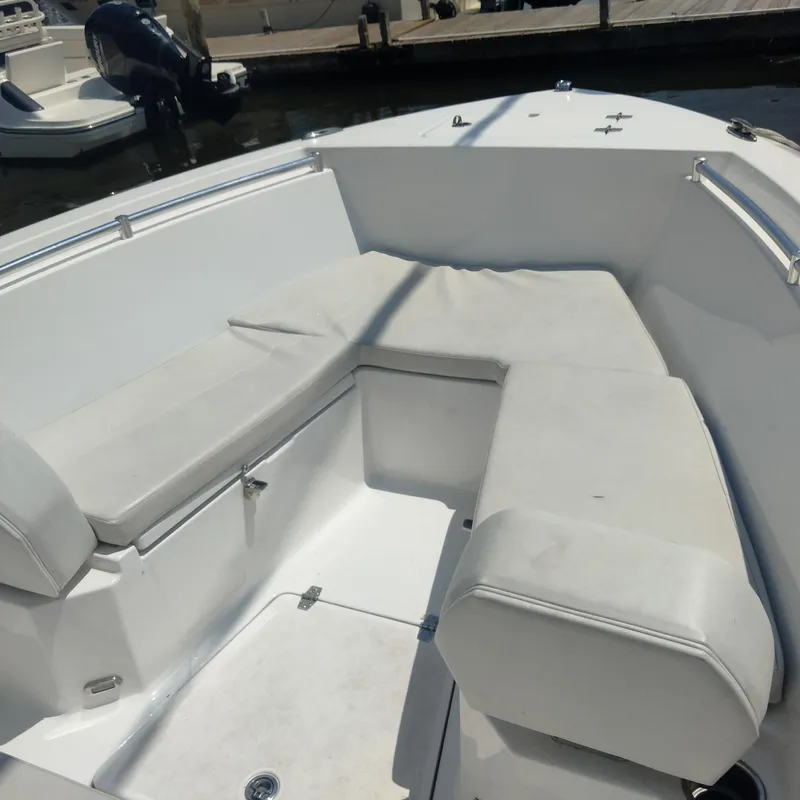Slide: The Image of 2024 Aquasport 2200 Center Console boat with cushioned seating, docked at marina. - 8