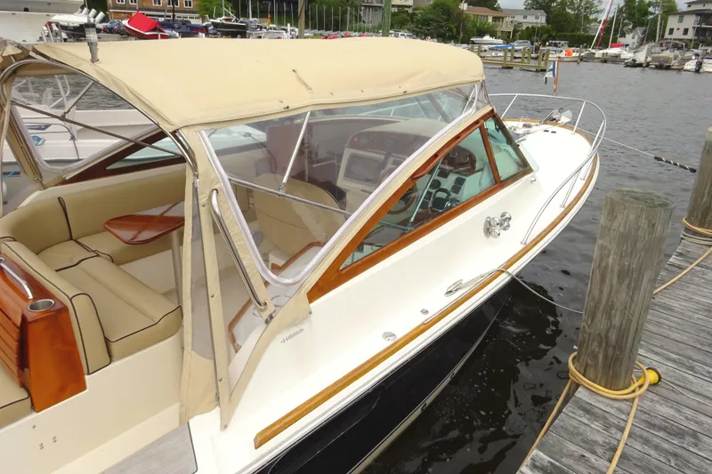 Slide: The Image of 2009 Hunt Yachts Harrier 29 docked, featuring beige canopy and elegant wood accents. - 10