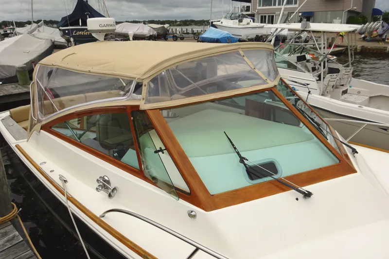 Slide: The Image of 2009 Hunt Yachts Harrier 29 docked, featuring a beige canopy and wooden trim. - 11