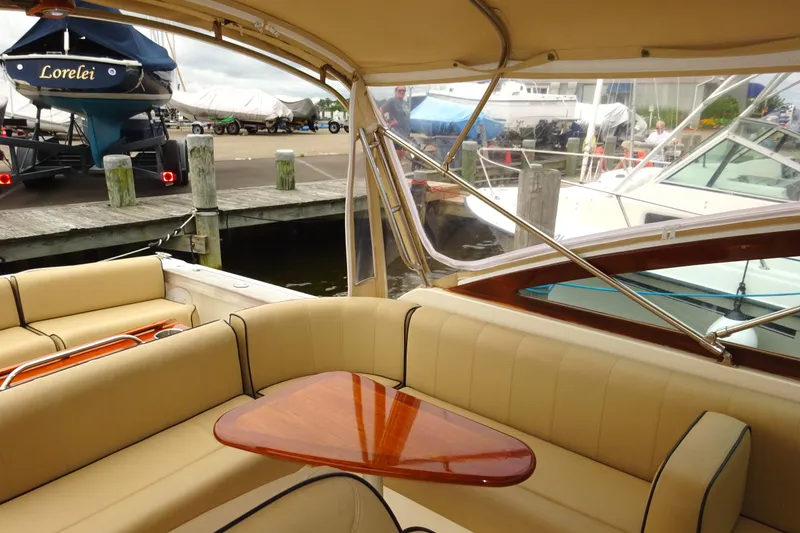 Slide: The Image of 2009 Hunt Yachts Harrier 29 interior with beige seating and wooden table at a marina. - 21