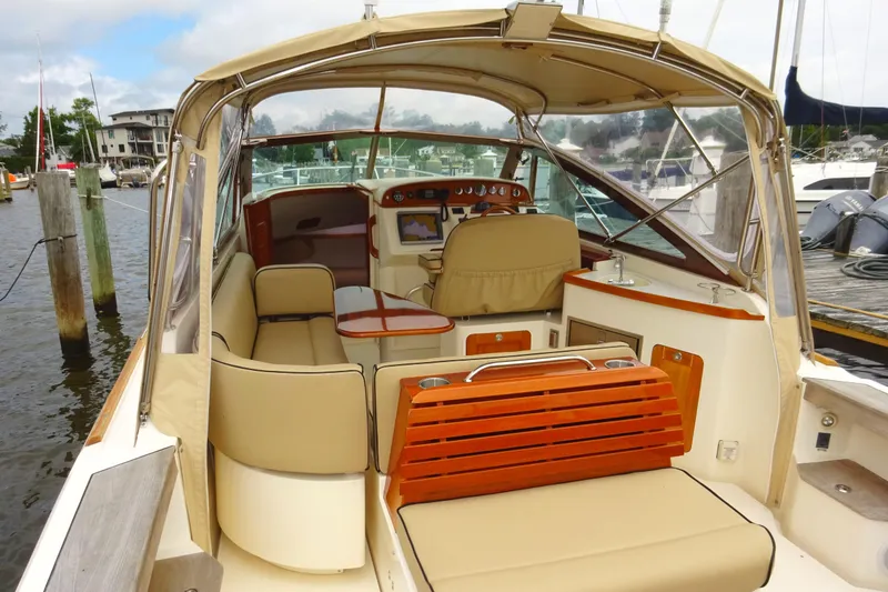 Slide: The Image of 2009 Hunt Yachts Harrier 29 interior with beige seating and wooden accents at a marina. - 23