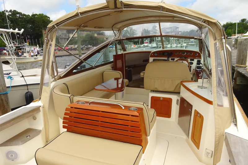 Slide: The Image of 2009 Hunt Yachts Harrier 29 interior with beige seating and wooden accents at a marina. - 25