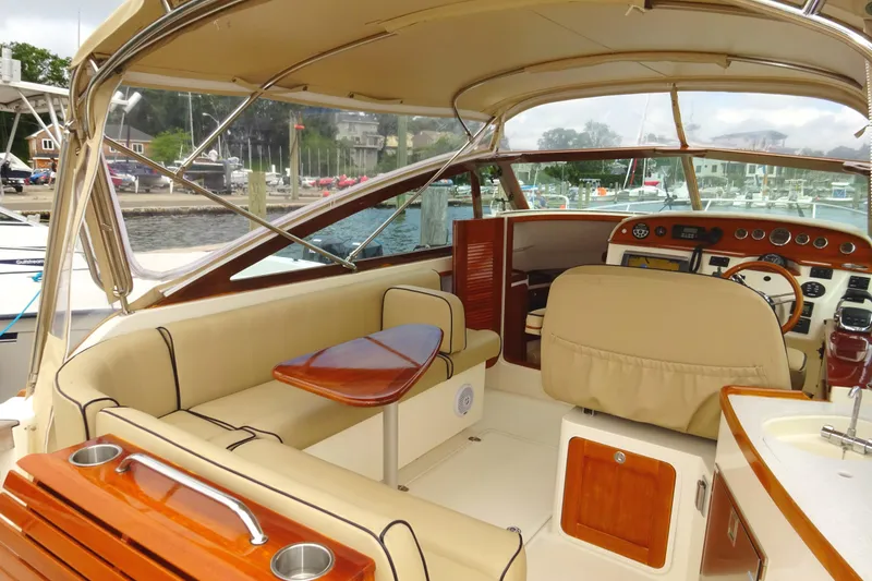 Slide: The Image of 2009 Hunt Yachts Harrier 29 interior with beige seating and wooden accents at a marina. - 29