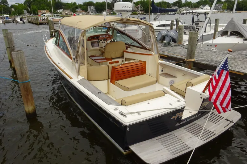 Slide: The Image of 2009 Hunt Yachts Harrier 29 docked, featuring beige seating and American flag. - 8