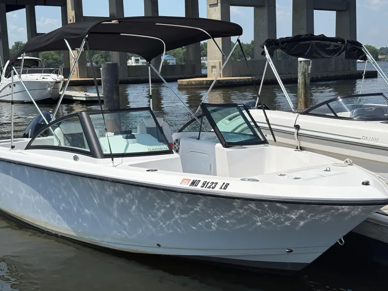 Slide: The Image of 2023 Aquasport 2200 Dual Console boat docked by the water. - 2