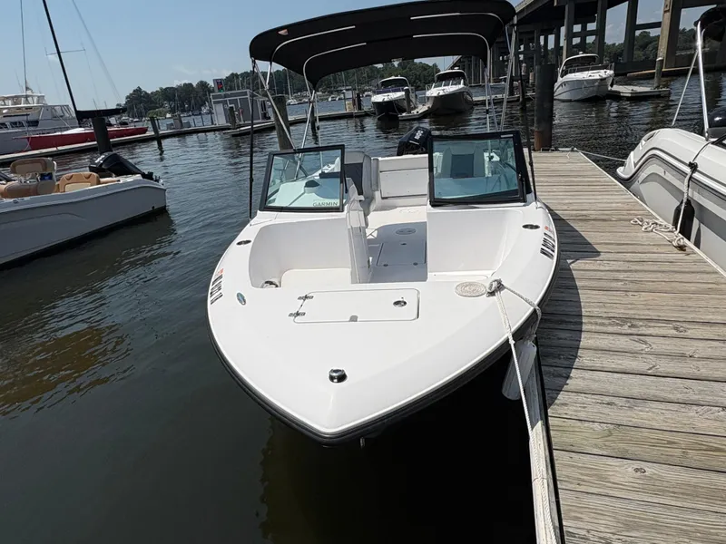 Slide: The Image of 2023 Aquasport 2200 Dual Console boat docked at marina, featuring sleek design and canopy. - 3