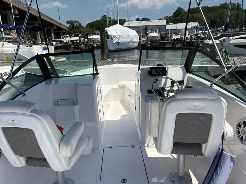 Slide: The Image of 2023 Aquasport 2200 Dual Console boat interior at marina, featuring steering wheel and seating. - 6