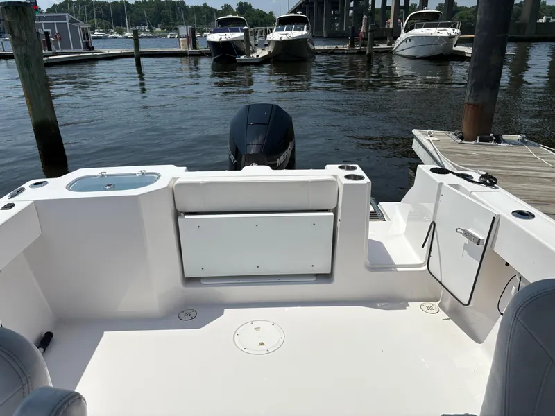 Slide: The Image of 2023 Aquasport 2200 Dual Console boat interior at marina, featuring seating and storage. - 7