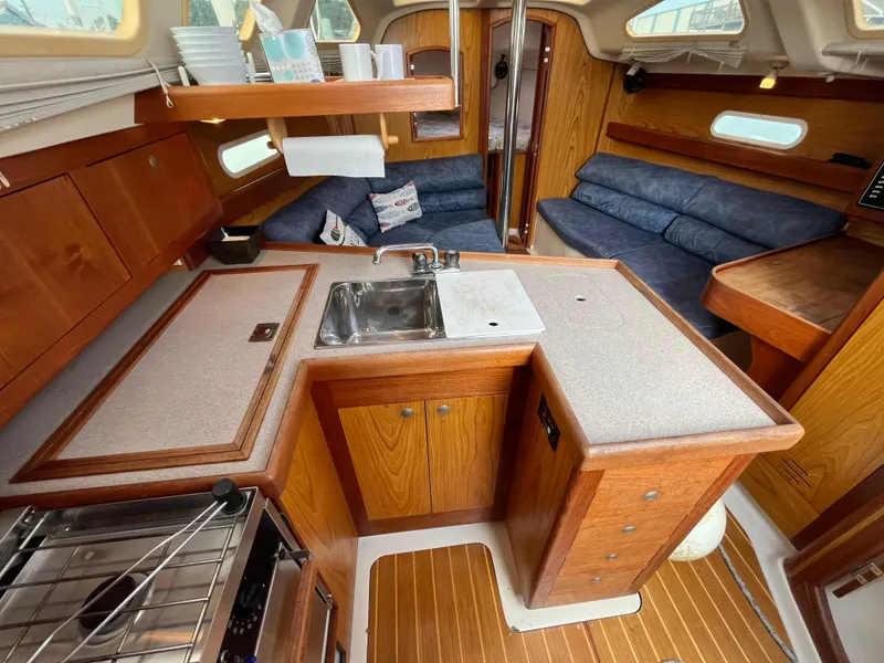 Slide: The Image of Interior of a 2000 Hunter 340 sailboat featuring a compact kitchen and seating area. - 37