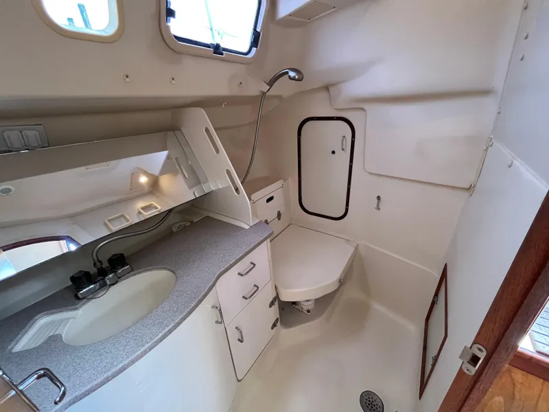 Slide: The Image of Compact bathroom in a 2000 Hunter 340 sailboat, featuring sink, shower, and storage. - 45