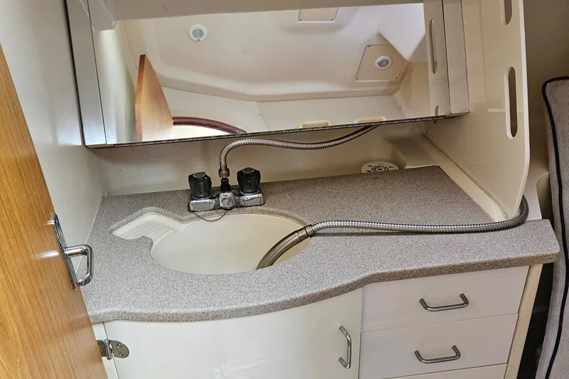 Slide: The Image of Compact bathroom sink in a 2000 Hunter 340 sailboat, featuring a mirror and storage drawers. - 46