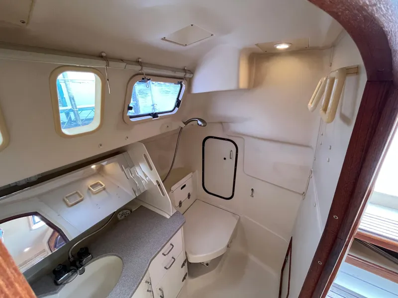 Slide: The Image of Interior of 2000 Hunter 340 sailboat bathroom with sink, mirror, and portholes. - 47