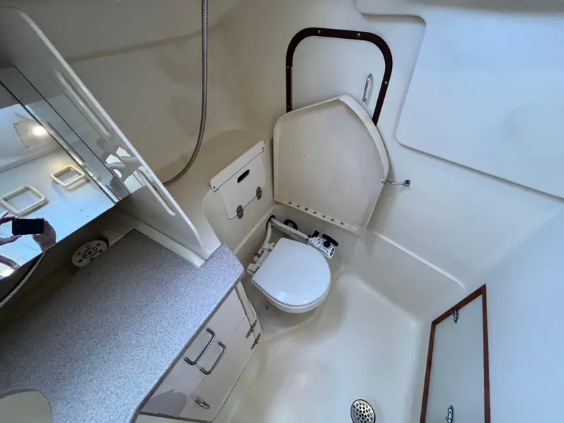 Slide: The Image of Compact bathroom in a 2000 Hunter 340 sailboat, featuring a toilet and storage cabinets. - 49