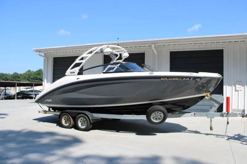 Slide: The Image of 2022 Yamaha Boats 252S on trailer, parked outside a storage facility under clear blue sky. - 1