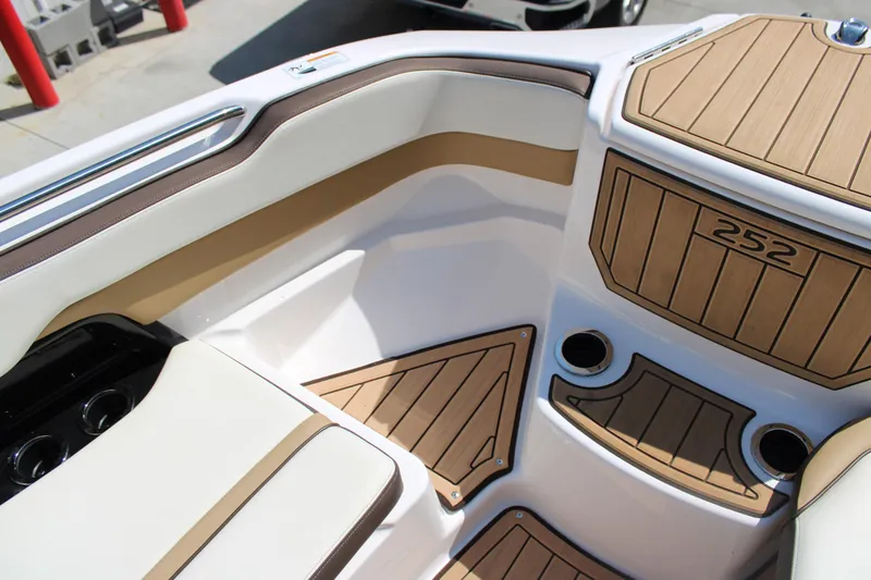 Slide: The Image of 2022 Yamaha Boats 252S interior with tan and white seating, wood accents, and cup holders. - 6