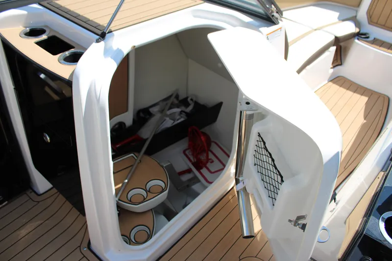 Slide: The Image of 2022 Yamaha Boats 252S interior storage compartment with cup holders and teak flooring. - 8