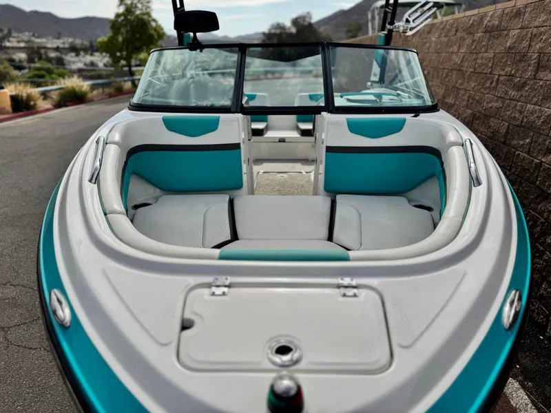 Slide: The Image of 2015 Chaparral Vortex 203 VRX boat with teal and white interior, parked outdoors. - 10