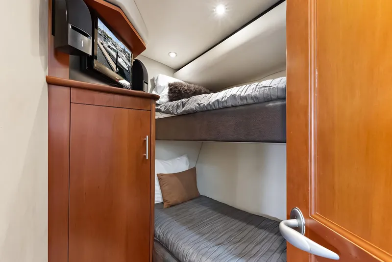 Slide: The Image of Bunk beds in 2006 Sea Ray 60 Sundancer yacht cabin with wooden cabinetry and TV. - 6